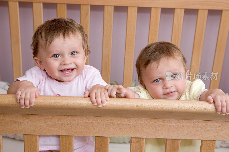 人- 10个月大的双胞胎女孩在婴儿床